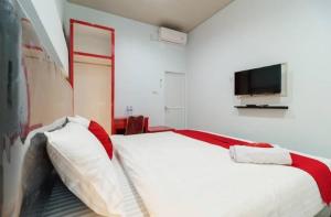 um quarto com uma grande cama branca e uma televisão na parede em RedDoorz Plus near Palembang Icon Mall 2 em Palimbão