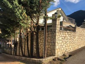 a house with a stone wall and a fence at Porfyra Luxury Guesthouse in Kalavrita