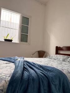 ein Schlafzimmer mit einem Bett mit einer blauen Decke darauf in der Unterkunft Casa Bela in Praia Grande