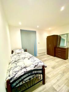 a bedroom with a bed and a dresser and a mirror at Comfortable One Bedroom Flat with free Car Park in London in London