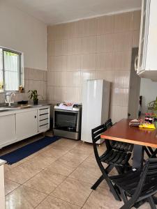 a kitchen with a table and a white refrigerator at Casa Bela in Praia Grande