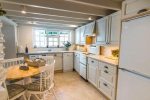 a kitchen with white cabinets and a wooden table at Boscastle Quaint Cornish Fishermans Cottage in Boscastle