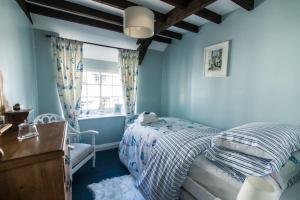 a blue bedroom with a bed and a window at Boscastle Quaint Cornish Fishermans Cottage in Boscastle