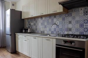 cocina con armarios blancos, fregadero y fogones en AS apartmán sever, en Košice