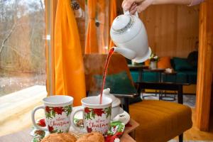 a person pouring a drink into two coffee mugs at Vikendica Đoković 2 - Jahorina in Pale