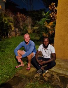 two men sitting on the steps of a house at TGS Homestay in Kampala