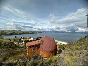 Lago de Tota Playa Blanca-Glamping Kairos في توتا: مبنى قديم على تلة بجانب تجمع المياه