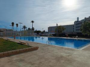 une grande piscine dans une ville bordée de palmiers dans l'établissement Playa Cannet del Berenguer 7 pers piscina tennis, à Canet d'En Berenguer