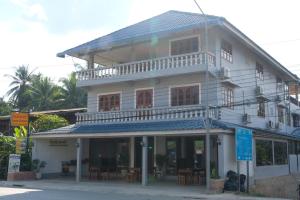 a white building with a balcony on a street at Sabaydee Guesthouse in Ban Houayxay