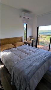 a large bed in a bedroom with a large window at Complejo Bosques in Villa Serrana