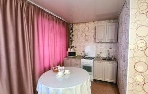 a small kitchen with a table and pink curtains at 1 комнатная квартира в центре in Uralsk