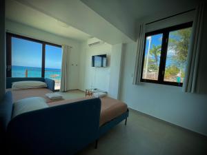 1 dormitorio con 2 camas, sofá y ventana en 1 Corcega Beachfront Suites, en Rincón