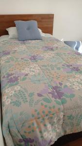 a bed with a colorful comforter with a blue pillow at Valdivia Tralcao Lodge 2 in Valdivia