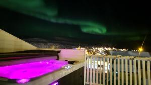 a hot pink bath tub on a balcony at night at Nord Hus Service AS, Deluxe, Sauna, Jakuzzi in Havøysund