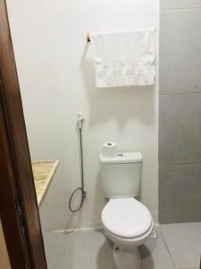 a white bathroom with a toilet and a towel at Suite Compacta Wind Jeri in Jericoacoara