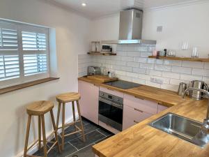 a kitchen with a sink and a counter with stools at Luxurious cottage in the heart of Falmouth in Falmouth