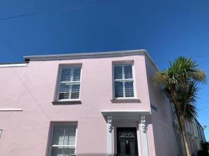 a pink house with a palm tree in front of it at Luxurious cottage in the heart of Falmouth in Falmouth