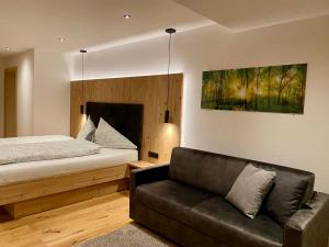 1 dormitorio con 1 cama y 1 sofá en Chalet & Almhostel Alpenperle - Selbstversorger Unterkunft, en Tannheim