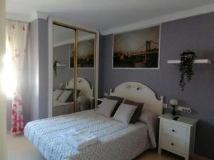 um quarto com uma cama branca e um espelho em Habitaciones Torremolinos em Torremolinos