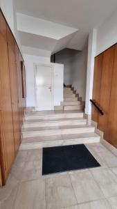 einen Flur mit einer Treppe mit einer weißen Tür und einem schwarzen Teppich in der Unterkunft Sol y Nieve Campoo in Reinosa