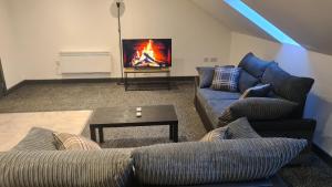 uma sala de estar com 2 sofás e uma televisão de ecrã plano em Homestay by BIC Oates 9 em Dewsbury