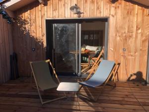2 chaises et une table sur une terrasse en bois dans l'établissement La Cabane 14, à Lanton