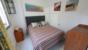 ein Schlafzimmer mit einem Bett mit einer gestreiften Decke in der Unterkunft Apartamentos Eduardo Rico in Nerja