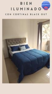 1 cama con edredón azul en un dormitorio en Departamento a estrenar GALO VII en San Bernardo