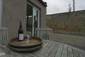 埃爾金的住宿－Elgin, home from home，一瓶葡萄酒和一张木桌上的玻璃杯