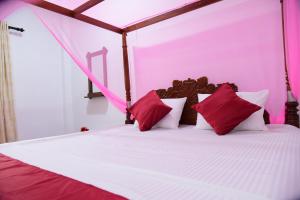 a bedroom with a bed with red and white pillows at GK Home Stay in Hikkaduwa