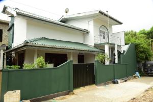 a house with a green fence in front of it at GK Home Stay in Hikkaduwa