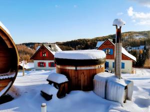 ein schneebedecktes Holzfass mit Häusern im Hintergrund in der Unterkunft Kolorowe Karkonosze in Preseka