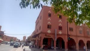 un edificio rojo en la esquina de una calle en hôtel hicham, en Ouarzazate