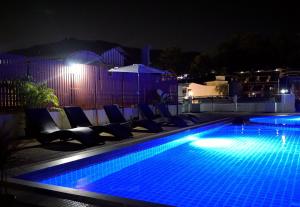 una piscina por la noche con sillas y sombrilla en Odin Andaman Hotel en Patong