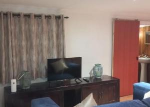 a living room with a tv and a blue couch at Timber Ally Cabin in Umtentweni