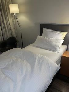 ein Bett mit weißer Bettwäsche, einer Lampe und einem Stuhl in der Unterkunft Hotel Lindenhof in Erkelenz