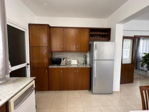 uma cozinha com armários de madeira e um frigorífico branco em Villa Andy-350 m from the beach em Lárnaca