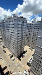 a tall building with cars parked in a parking lot at Apartamento 2 quartos completo com garagem in Juiz de Fora