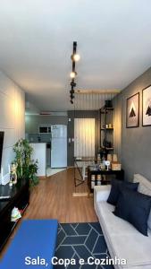 a living room with a white couch and a kitchen at Apartamento 2 quartos completo com garagem in Juiz de Fora