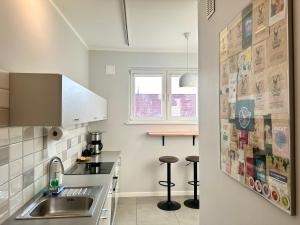 a kitchen with a sink and two bar stools at Apartament Willow in Gdańsk