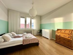 a bedroom with a bed and a dresser and a window at Apartament Willow in Gdańsk