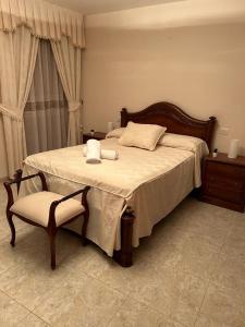 a bedroom with a large bed and a chair at Casa Ancá Los Abuelos in Rute