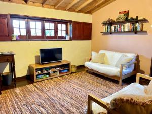 ein Wohnzimmer mit einem Flachbild-TV und einem Sofa in der Unterkunft Casa Via d'Agua in Fajã Grande in Faja Grande
