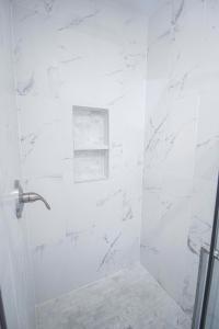 y baño con ducha y azulejos de mármol blanco. en Little Chi Cottages, en Noblesville