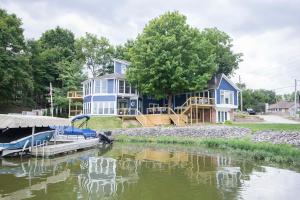 una gran casa azul con un barco en el agua en Little Chi Cottages, en Noblesville