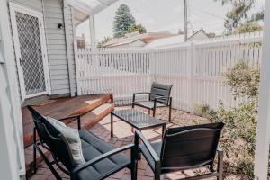 a patio with chairs and a wooden table and chairs at The Sage Cottage - Explore Bendigo CBD on foot! in Bendigo