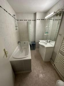 ein weißes Badezimmer mit einer Badewanne und einem Waschbecken in der Unterkunft Joli appartement 2 chambres face gare in Forbach