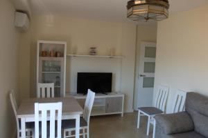 a living room with a table and a television at Baleares III Apartamento a 100 metros de la arena in Los Mártires