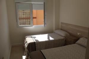 a small room with two beds and a window at Baleares III Apartamento a 100 metros de la arena in Los Mártires