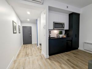 una sala de estar con paredes blancas y una cocina negra. en LE LOFT BLEU - Centre-Ville de Québec, en Quebec